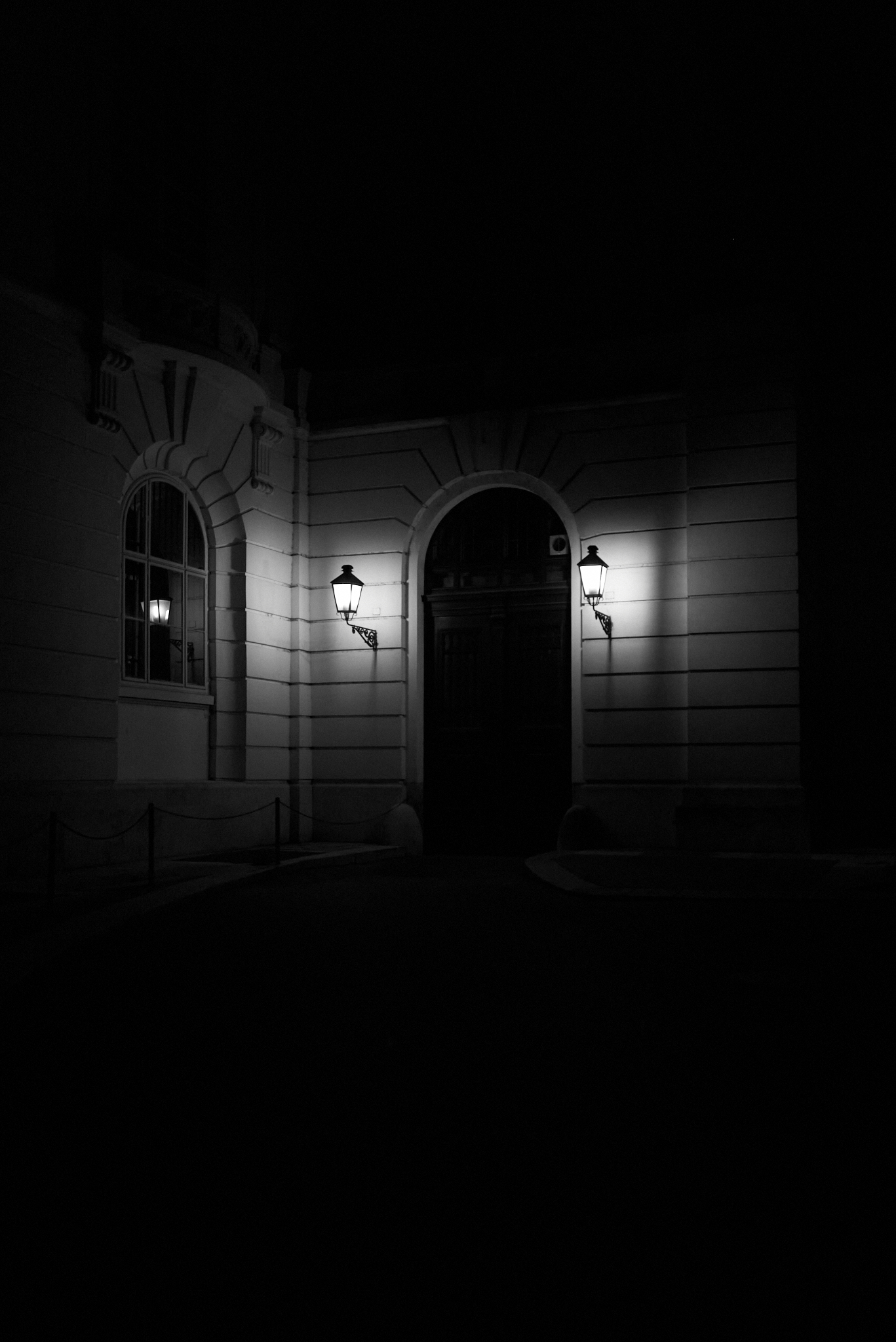 A door, at night, in the dark. A couple lamps.